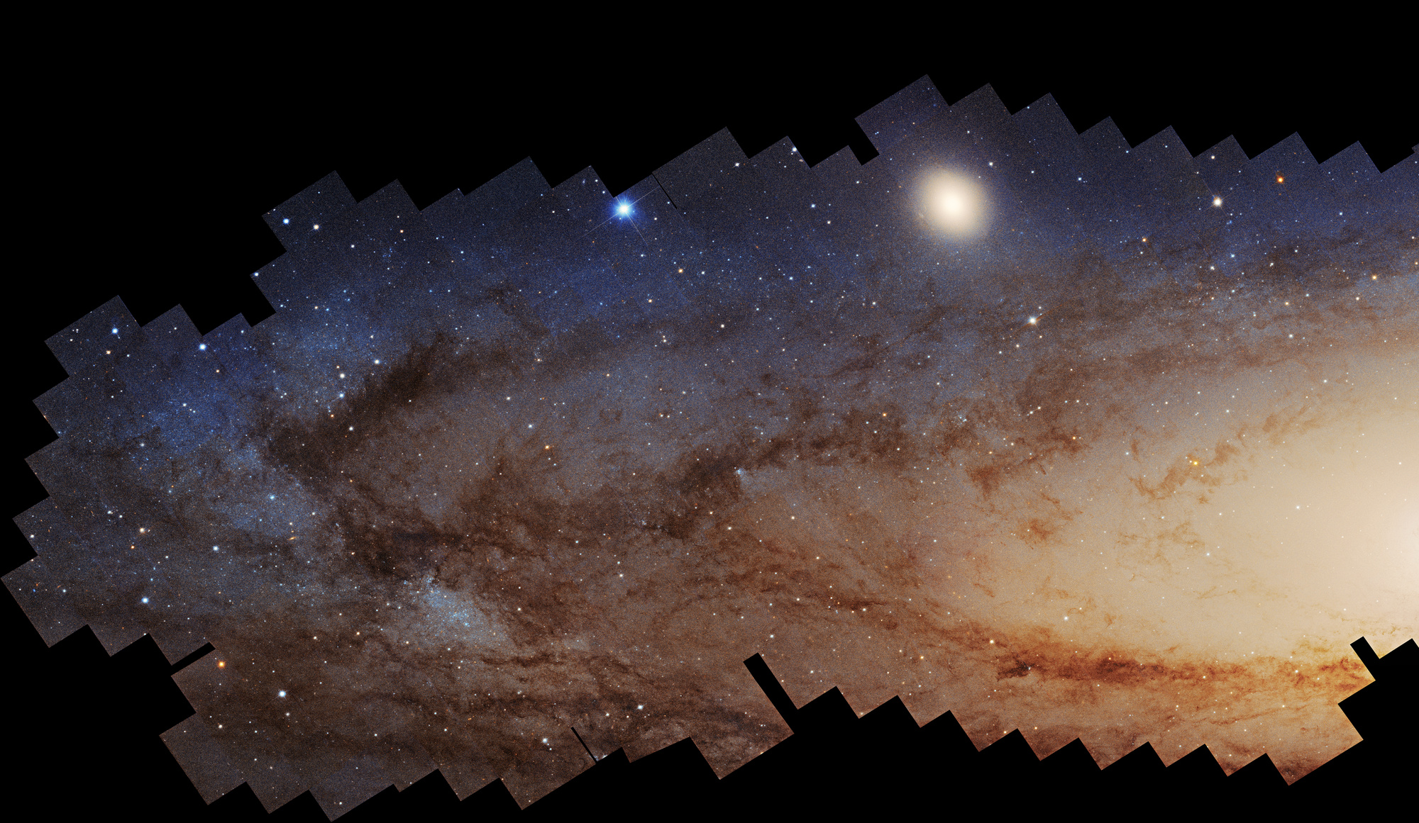 The Andromeda Galaxy crossing a black field, with its bright core and dark dust lanes visible