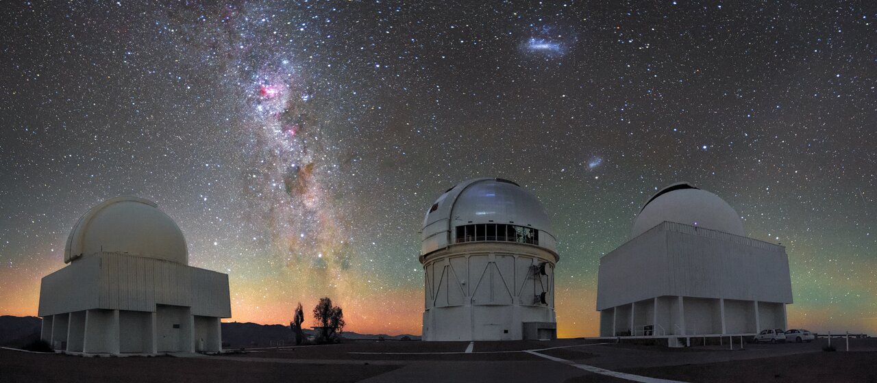 The Milky Way and Magellanic Clouds above telescope domes at Cerro Tololo in Chile