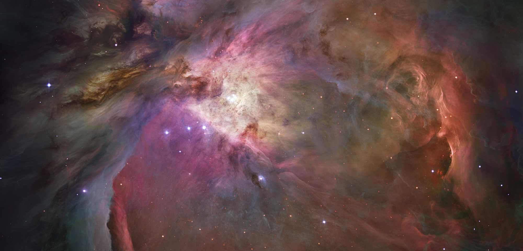The Orion Nebula filled with luminous gas, dark dust, and dense fields of young stars