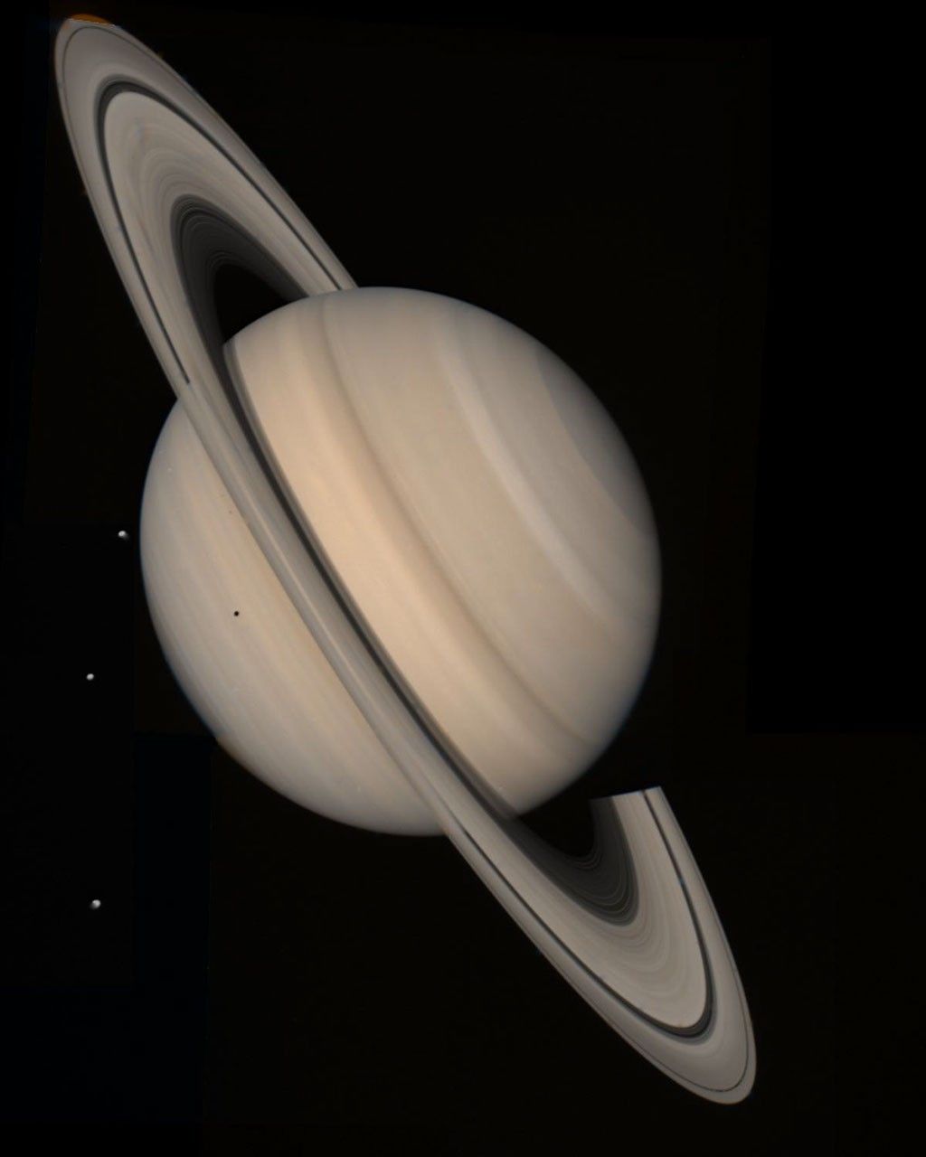 Saturn and its rings with three small moons visible nearby